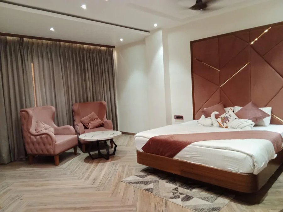 Guest room with armchairs and padded headboard at Hotel Awadh Palace, Khurai